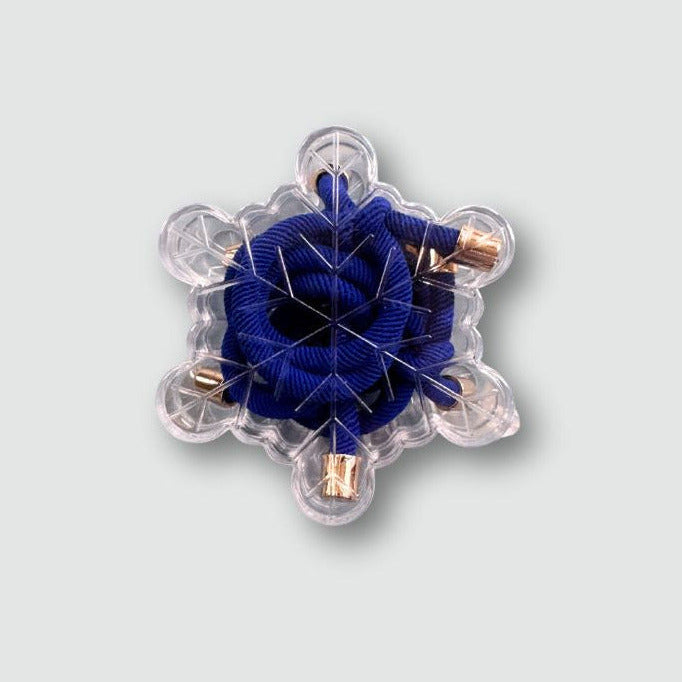 Decorative snowflake ornament with blue center and clear acrylic frame on a light gray background