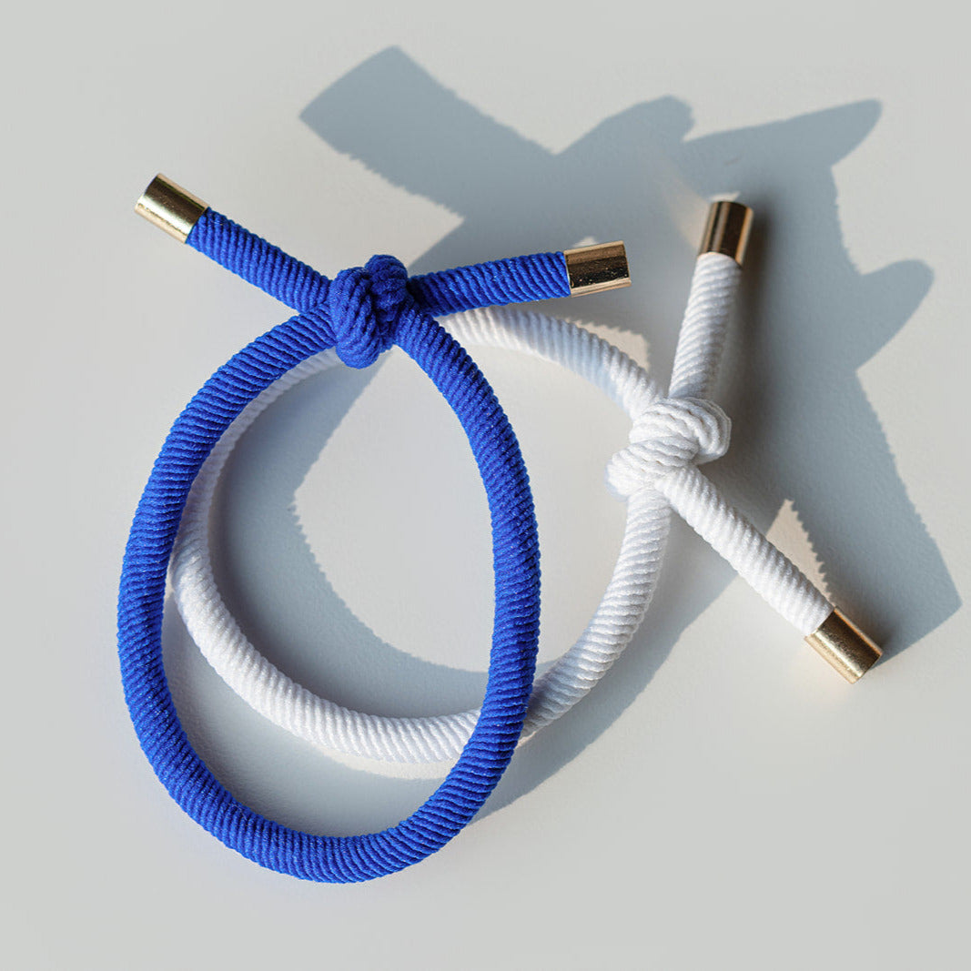 Blue and white braided hair tie bracelets with gold clasps on a light gray background