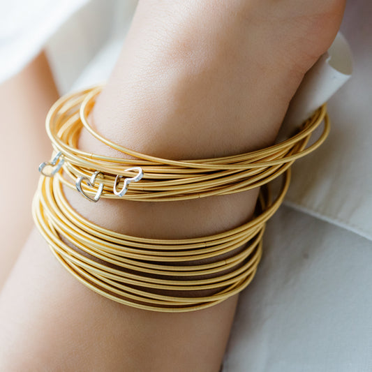 White Gold Cut Out Heart charm on Gold DIA on arm of model with more Gold DIA