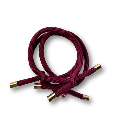 Burgundy hair ties with gold ends on a white background