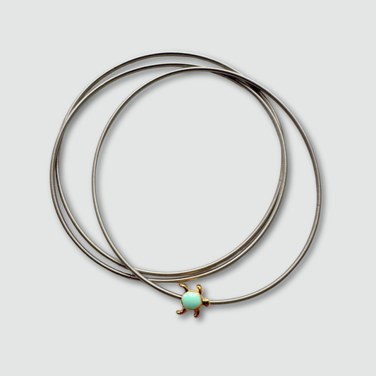 Set of three silver bracelets with a turquoise pendant on a light gray background