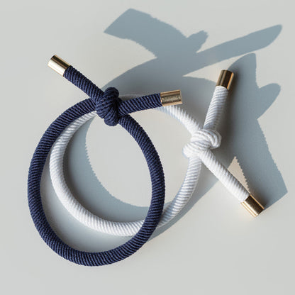 Navy and white hair ties with gold ends on a light gray background