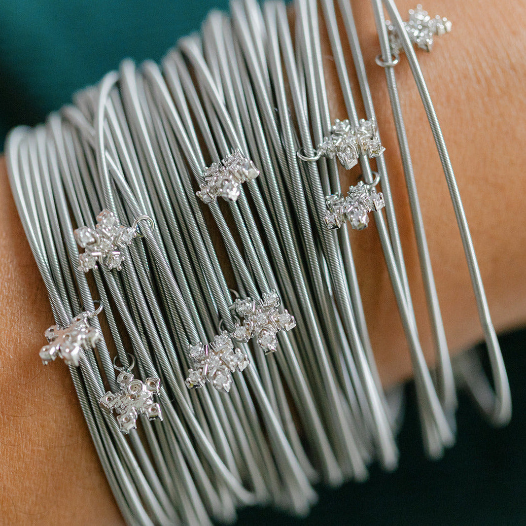 Silver bracelet with snowflake-shaped charms on a wrist against a blurred background