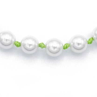 Pearl necklace with green knotted cording on a white background