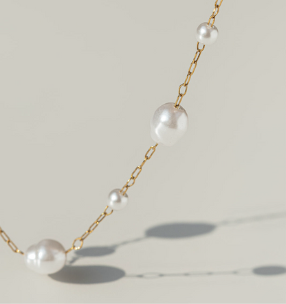 Pearl necklace with gold chain on a light background