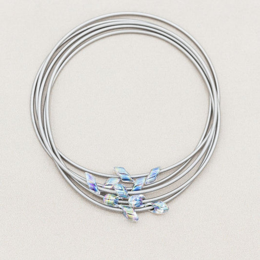 Silver wire bracelets with small crystals on a light beige background