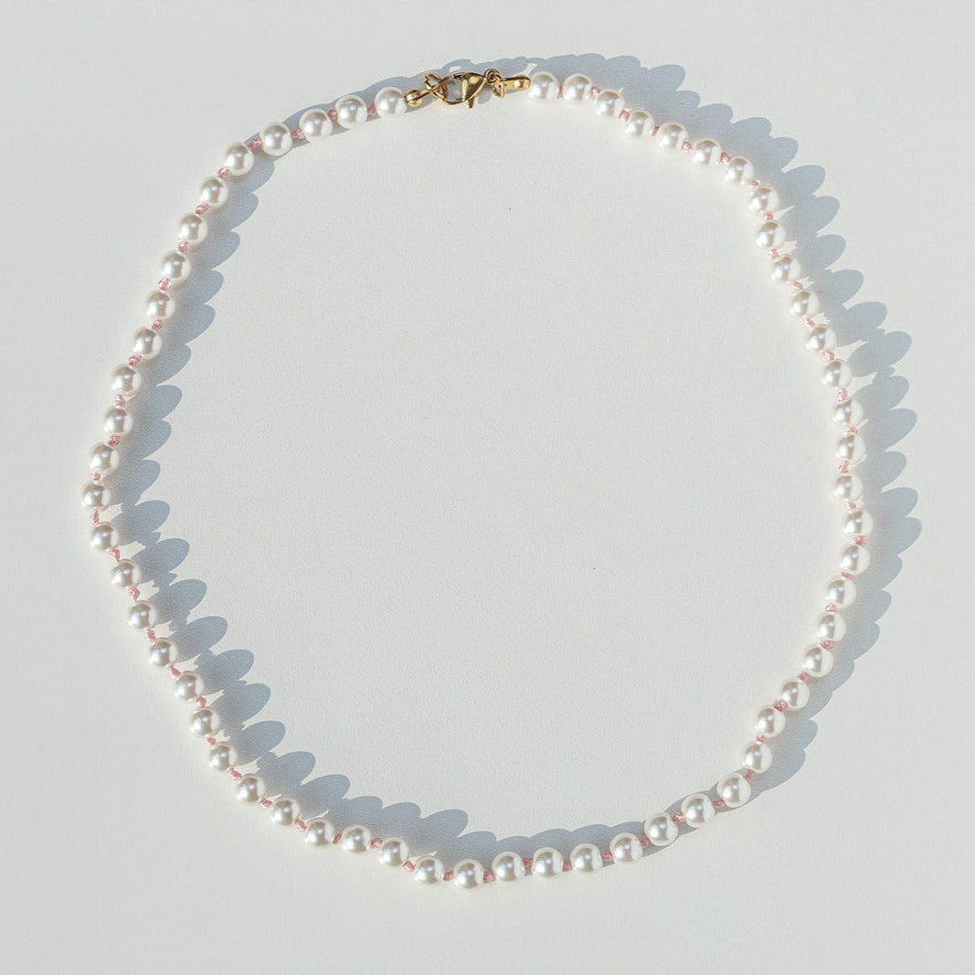 Pearl necklace on a light gray background
