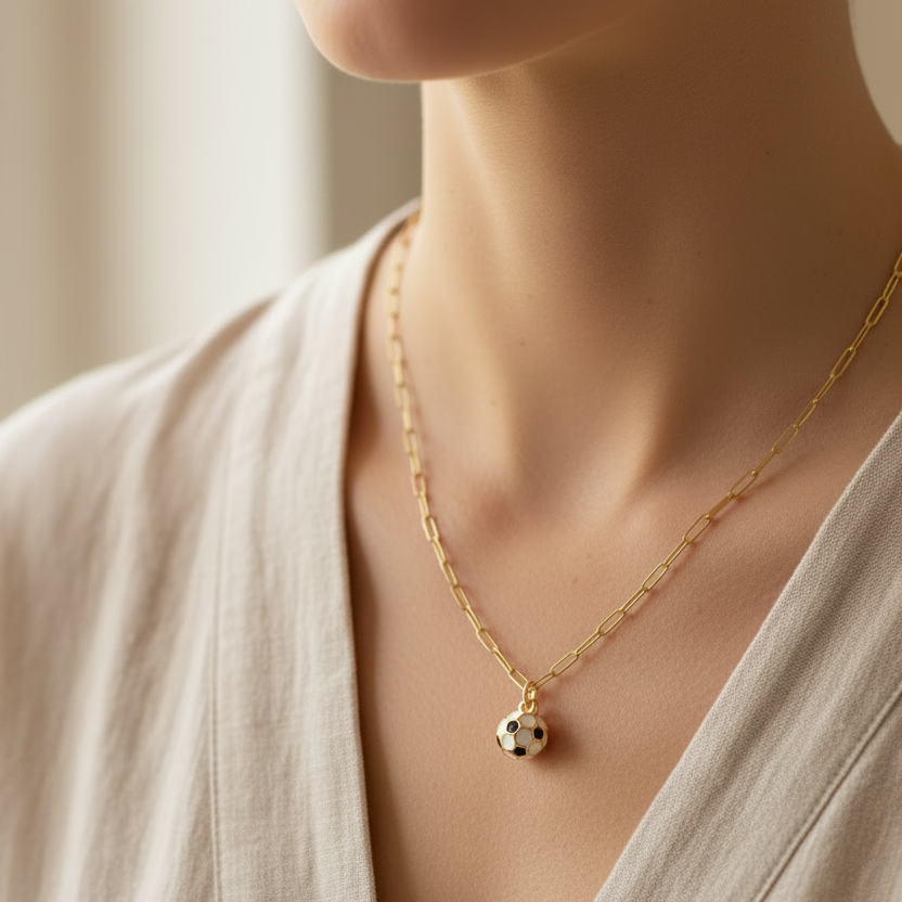 Model wearing gold paperclip chain necklace with soccer ball charm