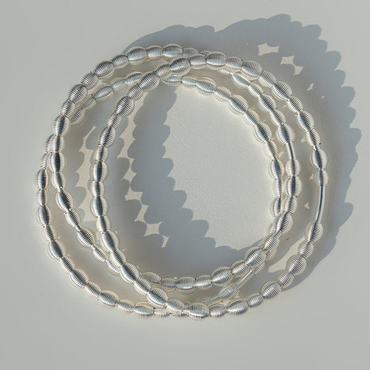Set of all beaded sterling silver dia bracelets on a light gray background