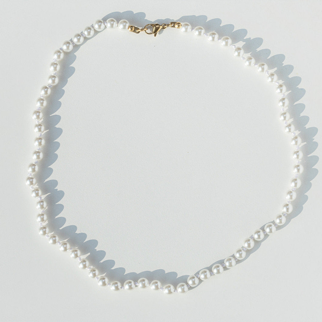 white hand knotted Pearl necklace on a light gray background