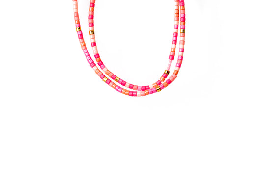 2 tiny beaded bracelets on string. Shades of tiny pink beads with a few gold beads throughout.
