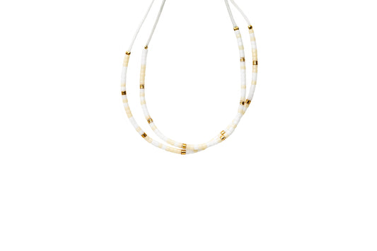 2 tiny beaded bracelets on string. Tiny white and cream beads with a few gold beads throughout.